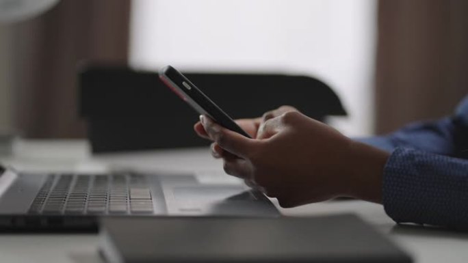 黑人妇女在办公室使用智能手机，用小工具特写镜头，在社交网络中查看新闻磁带，发送消息