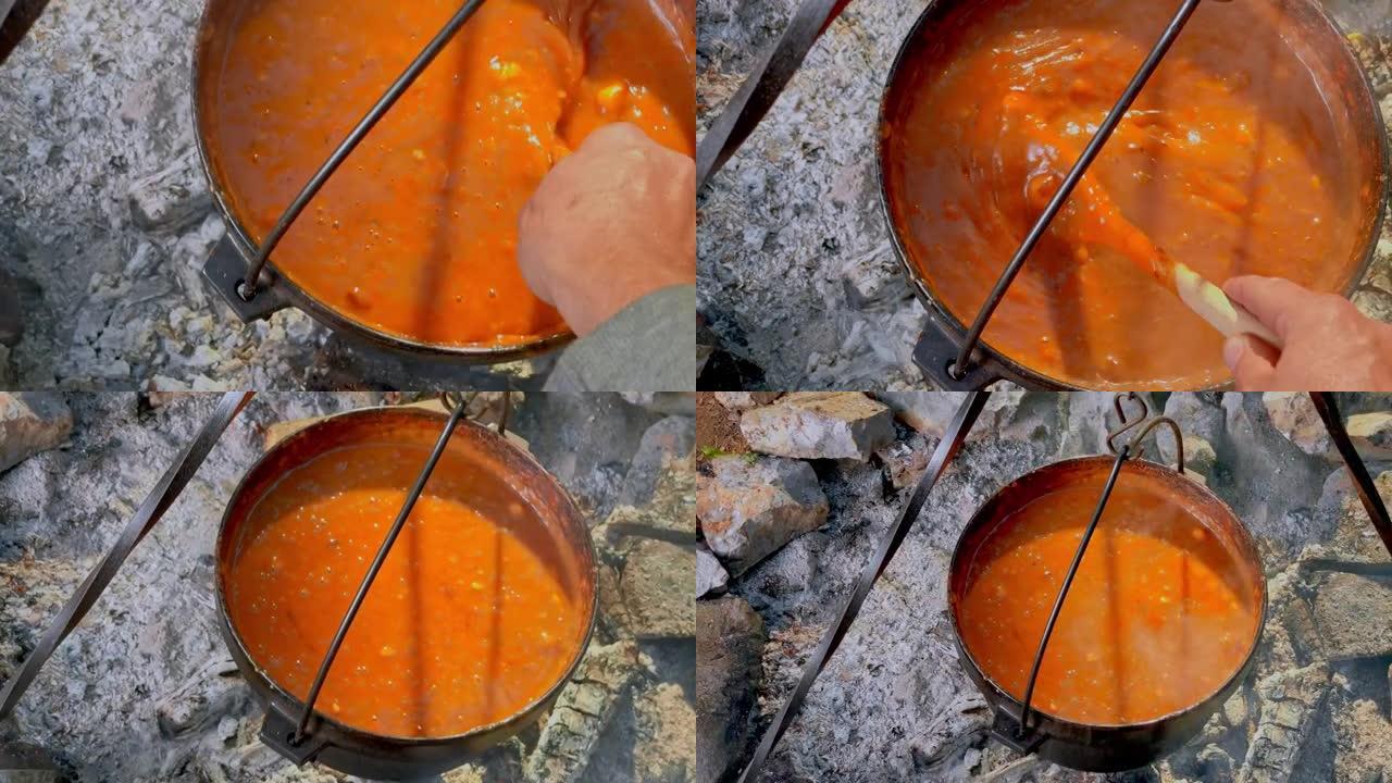 POV人在篝火上搅拌铸铁锅中冒泡的炖肉