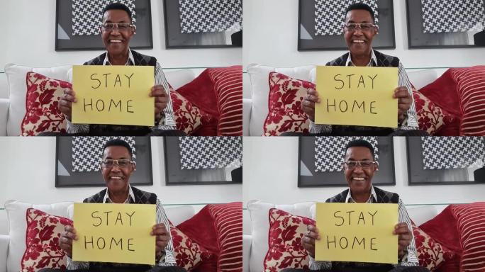 高级男子在视频通话中展示带有 “待在家里” 的纸张-网络摄像头的观点