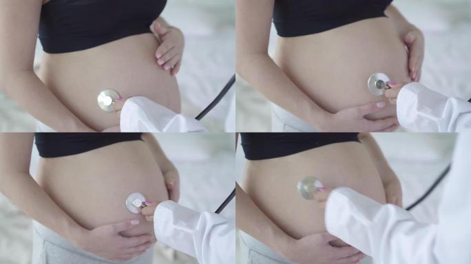 怀孕女性高加索腹部特写无法辨认的医生用听诊器听胎儿心跳。怀孕期间接受医学检查的年轻孕妇。