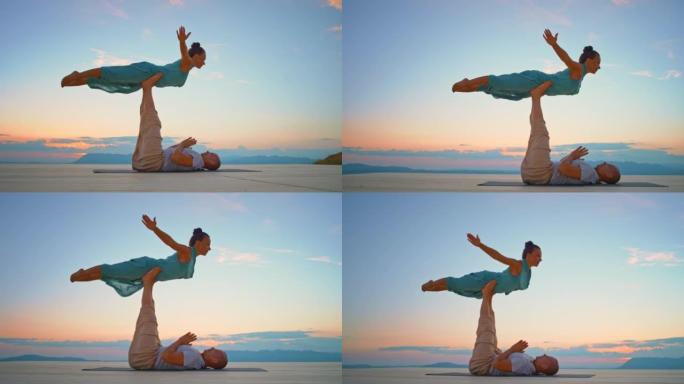 CS女人在日落时被她的瑜伽伴侣在山顶上举起