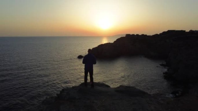 人的鸟瞰图暂停欣赏地中海悬崖边缘的景色，日落