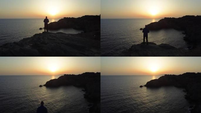 人的鸟瞰图暂停欣赏地中海悬崖边缘的景色，日落