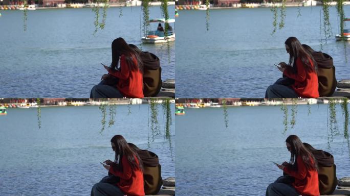 两位美女坐在湖边休息游船从背后驶过
