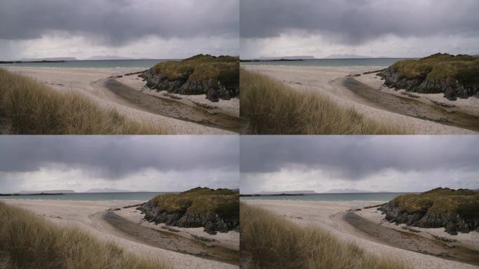 苏格兰的白色沙滩，河流流入大海，远处是多山的岛屿