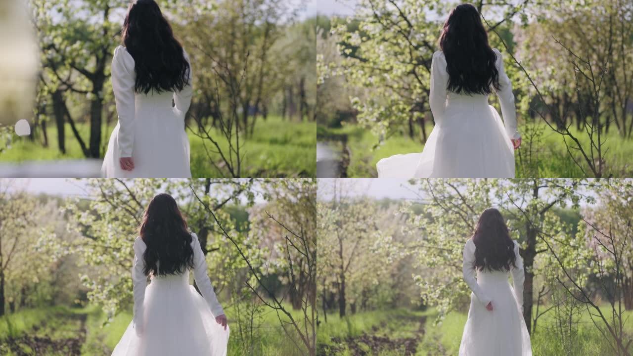 春天盛开的花园里美丽的新娘，穿着白色连衣裙的女性形象的后视图