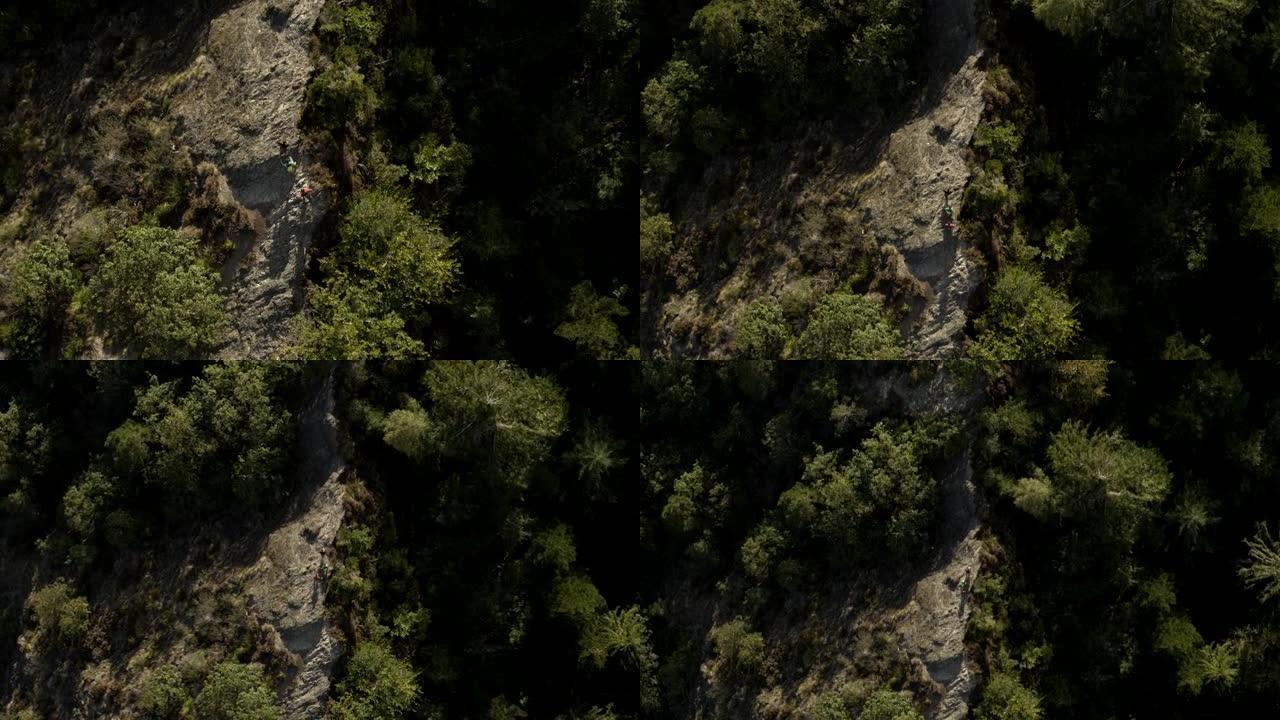 空中无人机拍摄了三名山地自行车手在岩石山脊上攀爬的镜头