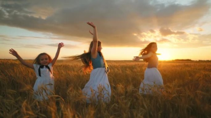 快乐的斯拉夫儿童女孩在日落的农田里的金色黑麦田上旋转，小姐妹们