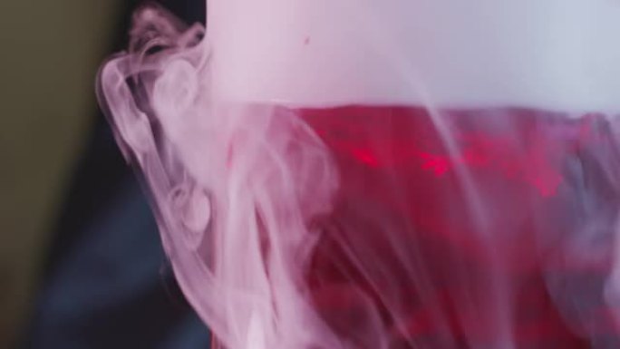 从红色液体烧杯中倒出的白色蒸汽的特写镜头