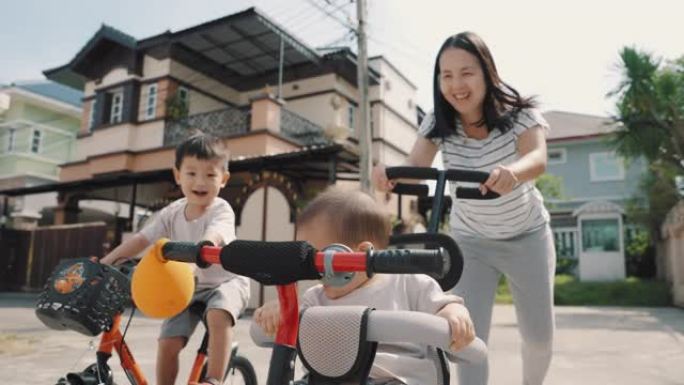 可爱的亚洲男孩和他的兄弟在户外骑自行车