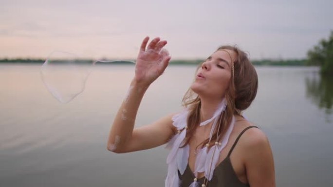 一位年轻的女孩艺术家使用肥皂泡展示魔术。在您的手中创建肥皂泡，并在日落时将其充气。