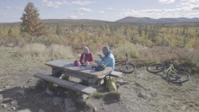 骑自行车后，男人和女人在野餐桌上休息