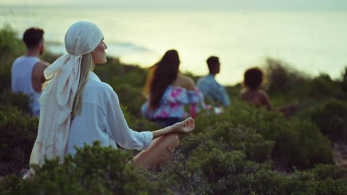一群不同的朋友坐在草崖上，一起放松。在莲花位置冥想
