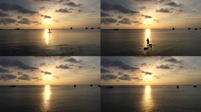日落时间海上女子桨板的鸟瞰图