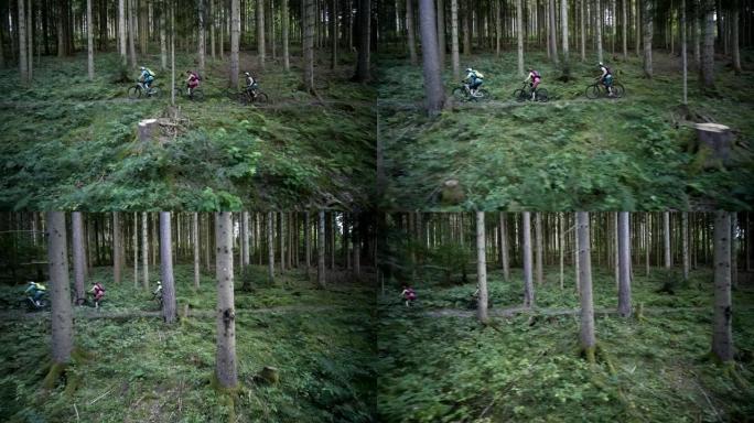空中无人机拍摄了三个骑在树林中的山地车手
