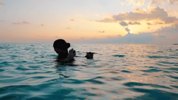一名潜水员从水中出来并在日落时取下面具的特写镜头