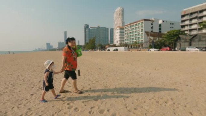 愉快的亚洲家庭在漫长的周末在海滩上享受时光。