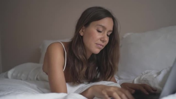 年轻女子在床上使用笔记本电脑