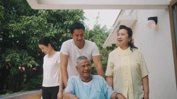 欢快的家庭推着年迈的父亲坐在家里的轮椅上。