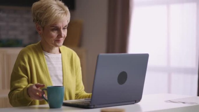 老年妇女正在通过笔记本电脑打字和发送信息，在社交网络中进行交流，上网和浏览网站