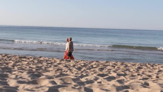 夫妇沿着空旷的海滩散步，交谈
