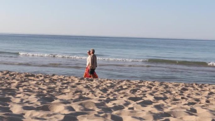 夫妇沿着空旷的海滩散步，交谈