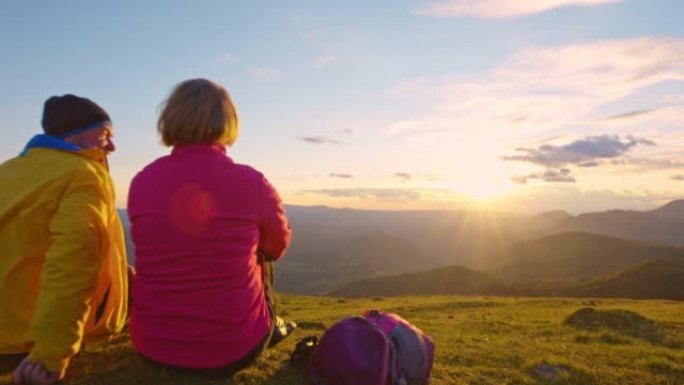 日落时分坐在山顶上的SLO MO CS高级徒步旅行夫妇