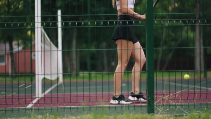 年轻女子的运动爱好，女士是在球场上弹跳网球和行走，下半身