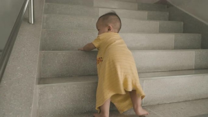 亚洲男婴在家里爬上台阶。