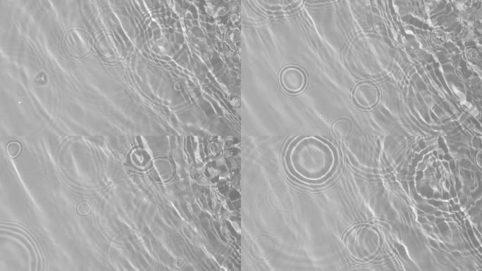 透明清晰的平静水面纹理，带有波浪、飞溅和气泡。时尚抽象自然背景。白灰色的水在阳光下波动。慢动作全高清