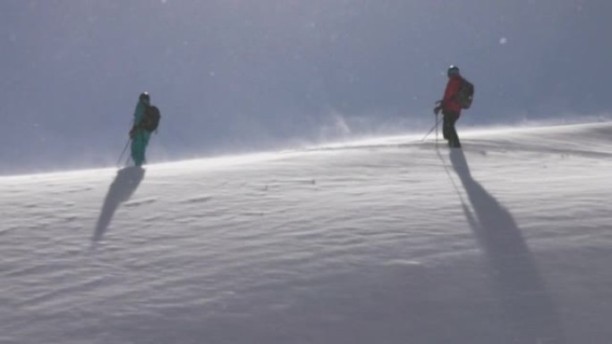 两个滑雪者沿着白雪皑皑的山坡徒步旅行