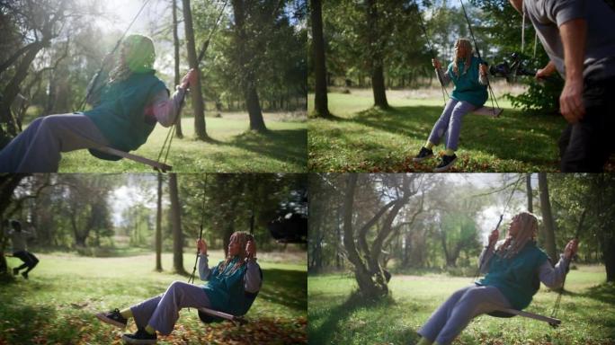 特写镜头男子用相机记录非洲族裔青少年在秋千公园的秋千上来回摆动