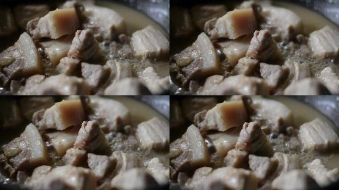 在锅里煮的猪肉肉是用冒泡的浓汤慢慢煮的。