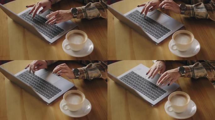 自由职业者的女人正在咖啡馆使用笔记本电脑，键盘和咖啡杯上的手的特写视图