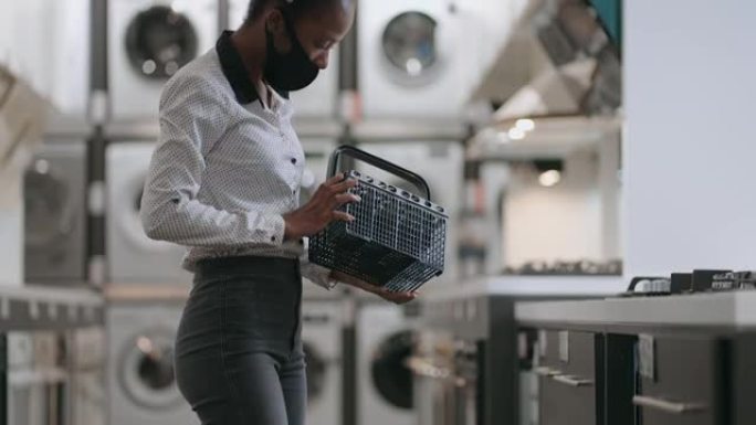 家用电器商店的女购物者，年轻的黑人妇女正在观看新型号的洗碗机