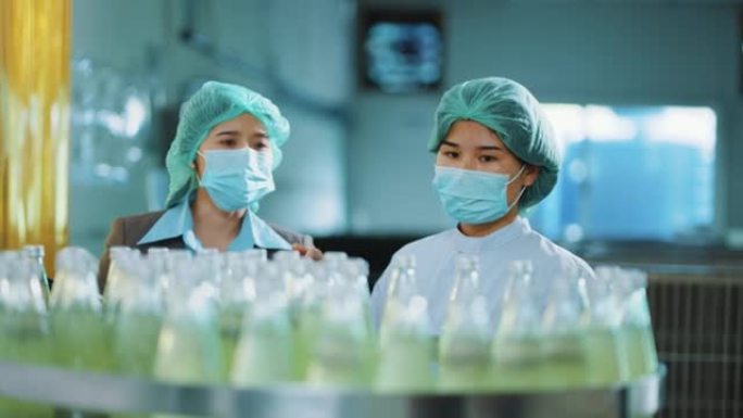两名生产工人在饮料厂检查产品。