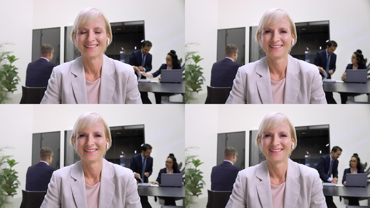 LD中年白人妇女戴着耳机在办公室微笑