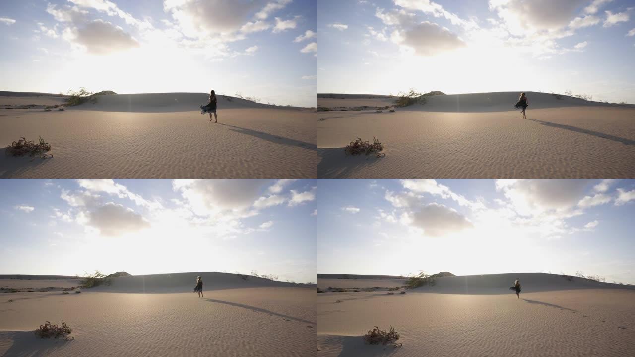一个穿着黑色连衣裙的女人在沙丘上逃离相机的距离镜头