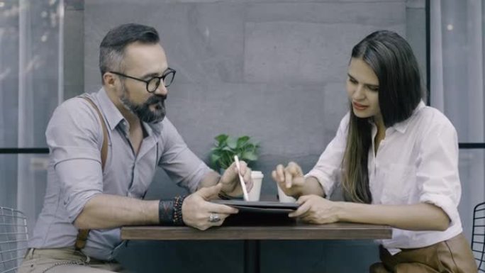 男子在咖啡厅向女友展示数字平板电脑上的东西