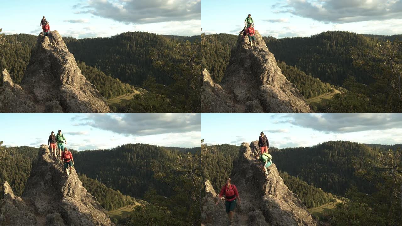 三名女自行车包装工在俯瞰森林的岩石小山上徒步旅行