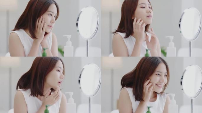 微笑的年轻美丽的亚洲女人，自然组成清新的皮肤照镜子，拍着脸。