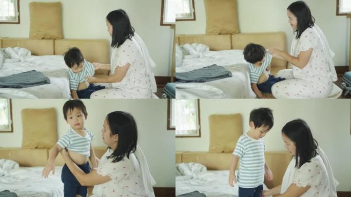 快乐的亚洲妈妈在家洗澡前给学龄前儿子脱衣服。