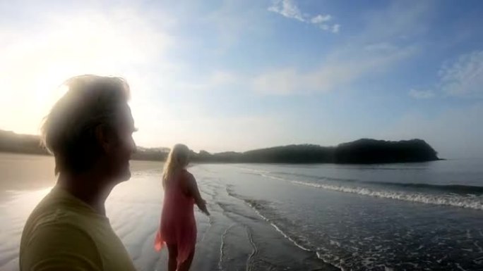 日出时，成熟的夫妇沿着空旷的海滩散步