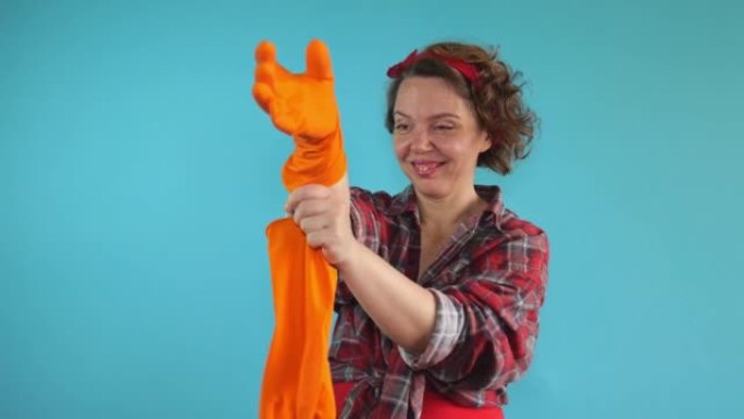 保洁者在蓝色孤立的背景上戴着橙色手套。穿着格子衬衫的清洁妇女的肖像
