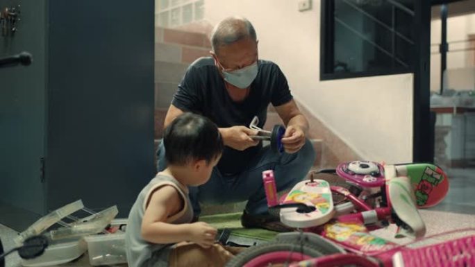 祖父在家为孙子修理儿童自行车。
