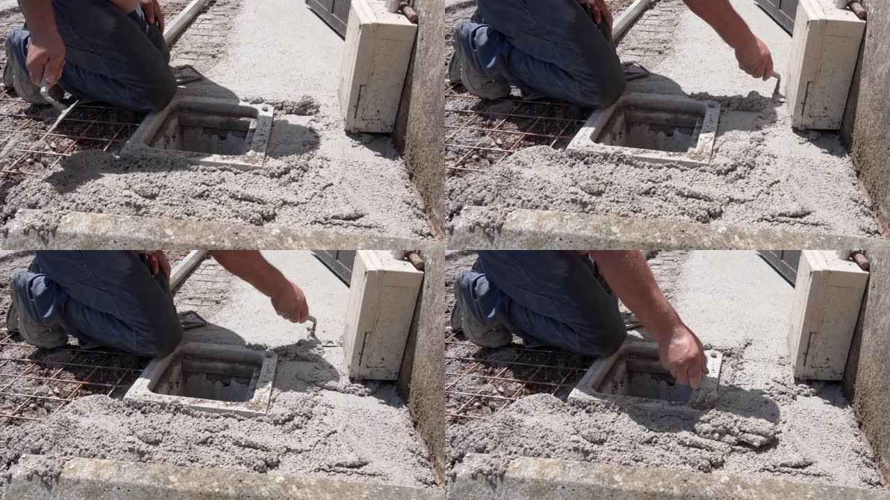 用工业金属抹子铺展和平整新鲜水泥溶液，修理工站在膝盖上，在施工现场平整液态混凝土钢筋基础网片。硬建筑