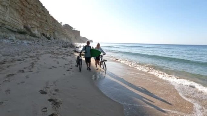 夫妇沿着空旷的海滩推自行车
