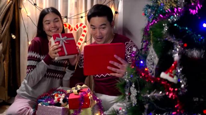 视频通话亚洲夫妇在家里的客厅为圣诞节送礼物