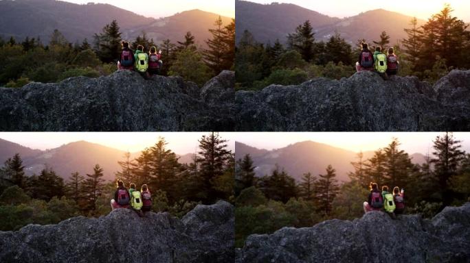 空中无人机拍摄的三名山地自行车手坐在日落时休息的岩石山脊上