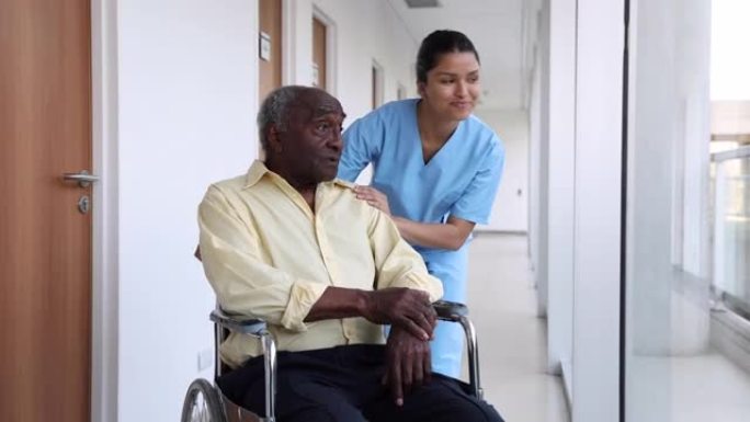 开朗的护士试图在辅助生活设施的轮椅上安慰黑人高级患者